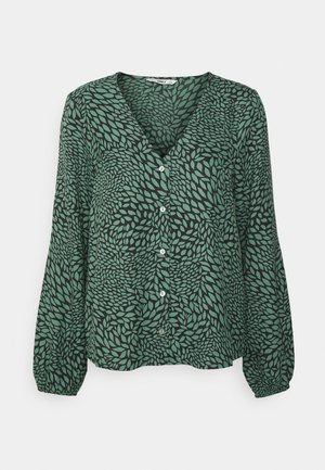 Blouse verte à manches longues boutonnée avec motif tourbillonnant de feuilles noires et poignets élastiques.