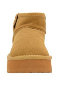 Stivale alla caviglia in suede beige con punta arrotondata, dettagli cuciti e suola in gomma marrone chiaro. Texture morbida e design a gambale corto.