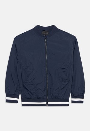 Navy blue zip-up bomber jacket with ribbed collar, cuffs, and hem featuring white stripes, front pockets, and lightweight fabric.