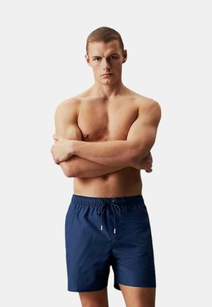 Costumi da bagno da uomo in blu navy realizzati in materiale leggero, dotati di una vita elasticizzata con cordoncino, texture liscia e un design semplice.