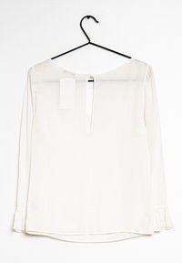 Blusa bianca a maniche lunghe con scollatura rotonda, apertura a chiave sulla schiena e polsini arricciati. Tessuto morbido con una leggera lucentezza.