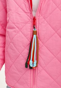 Prešívaná ružová bunda s červeným zipsom a viacfarebnou šnúrkou na zips. Materiál vyzerá ľahko a štruktúrovane.