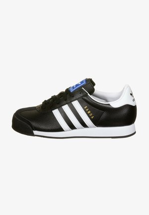 Czarny sneaker Adidas Samoa z białymi paskami, niebieskim logo na języku i białym paskiem na pięcie, widok z boku.