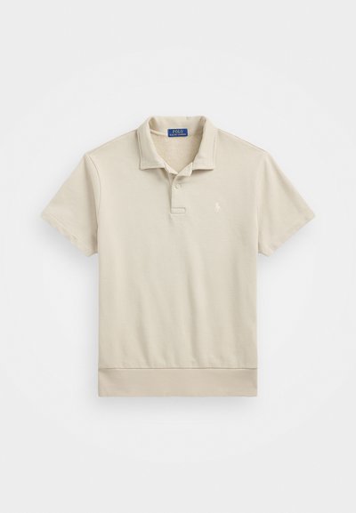 Polo beige à manches courtes, en coton, avec un col, deux boutons et un petit logo brodé sur la poitrine. Texture lisse.