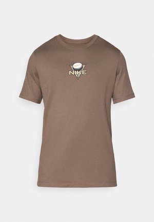 T-shirt de algodão castanho com decote redondo, mangas curtas e um logótipo triangular com uma bola de golfe e o texto "NIKE" em bordado dourado.