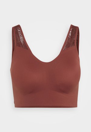 Brown sports bra with a smooth texture, wide straps, and mesh detailing along the shoulders. Features a v-neck design.