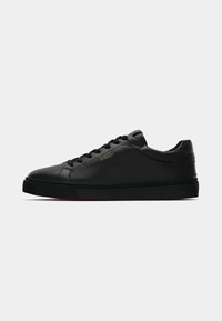Adidași negri din piele, cu un finisaj neted, bot rotund, talpă neagră plată și șireturi negre. Detaliu cu logo auriu pe latura exterioară.
