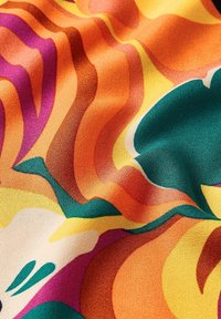 Tela colorida con patrones ondulados en tonos naranja, rosa, amarillo, verde y crema. La textura parece suave y ligeramente brillante.