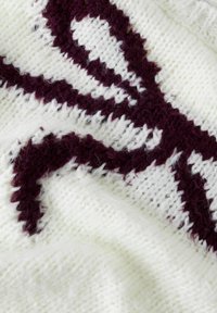 Maglione lavorato a maglia con base bianca e un motivo astratto color bordeaux. Tessuto morbido e testurizzato con punti visibili e peluria.