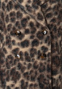 Doppelreiher-Mantel mit einem braun-beigen Leopardenmuster. Strukturiertes Gewebe mit schwarzen Akzenten und glänzenden braunen Knöpfen.