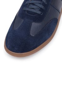 Zapatillas de deporte azul marino que combinan ante y cuero texturizado. Punta redondeada y suela de goma con un patrón sutil para mayor tracción.