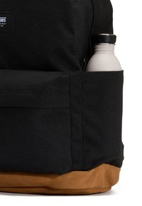 Svart ryggsäck i canvas med en botten av tanfärgat mocka. Sidoficka innehållande en grå vattenflaska med svart lock. Enkel, funktionell design.