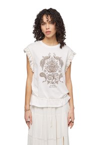 Top bianco a maniche corte con dettagli in frange, fantasia floreale e paisley, e la scritta "Go With the Flow" in marrone. Tessuto morbido, vestibilità rilassata.