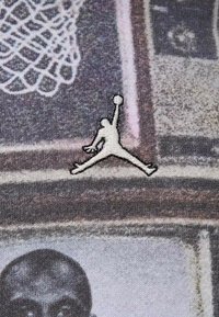 Tessuto bianco e nero con una stampa testurizzata che presenta immagini di basket. Logo Jumpman ricamato in bianco posizionato in modo prominente.