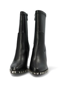 Botas de tobillo de cuero negro con un diseño ajustado, cremalleras laterales y acentos metálicos con remaches a lo largo de la suela. Textura suave y punta afilada.