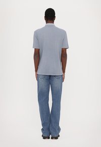 Gray short-sleeve polo shirt paired with light blue wide-leg jeans. The fabric appears smooth with a classic fit. Back view shown.