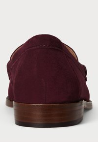 Burgundy suede loafers with a rounded heel and smooth wooden sole. Features minimal stitching and a relaxed slip-on design.
