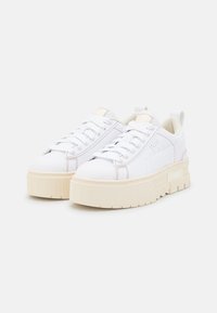 Vita sneakers med en kraftig krämfärgad sula, slät yta, snörning och subtil logotypdetalj på sidan. Minimalistisk design med rund tå.