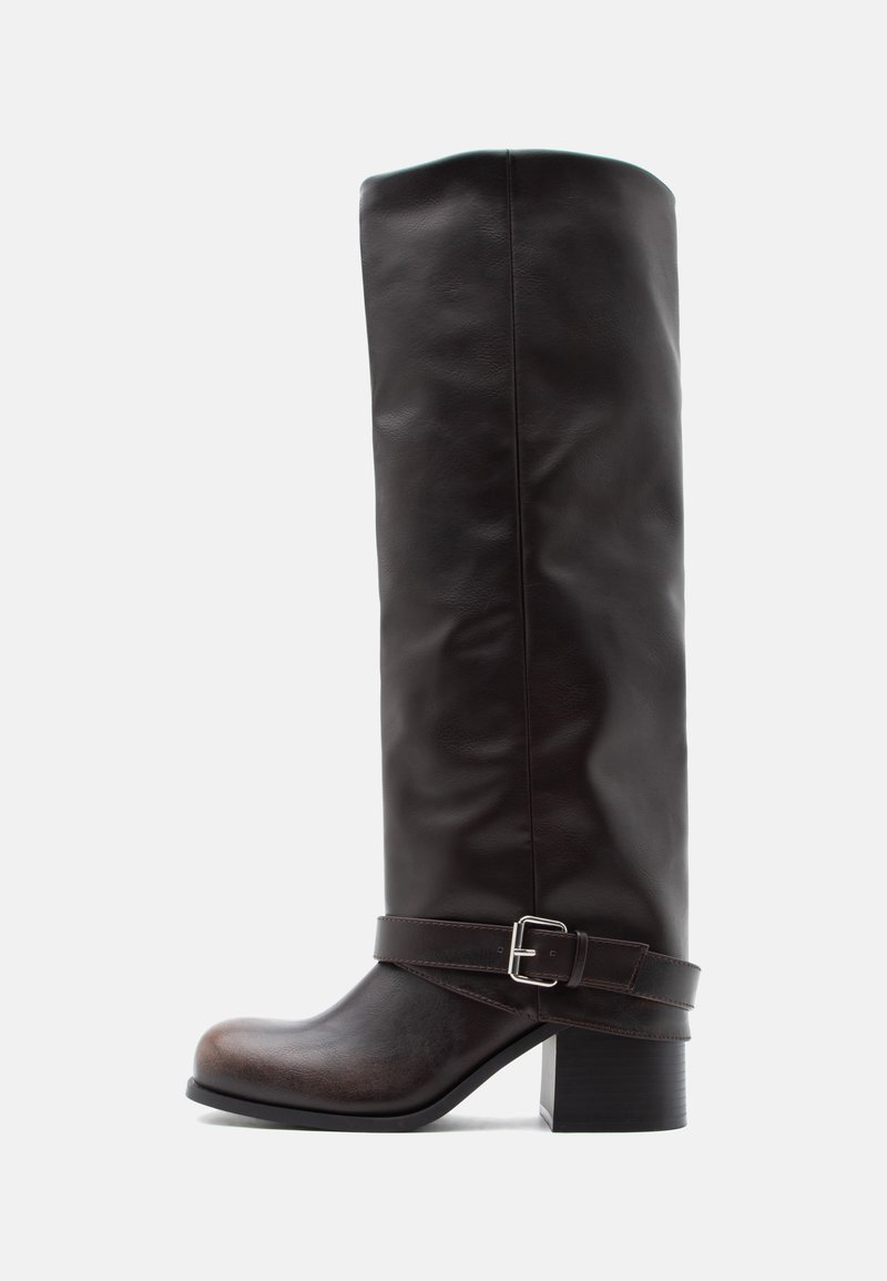 Σκούρο καφέ δερμάτινη μπότα μέχρι το γόνατο με στρογγυλεμένη μύτη, χαμηλό χο ντρό τακούνι και διακοσμητικό λουράκι με ασημένια αγκράφα κοντά στον αστράγαλο.