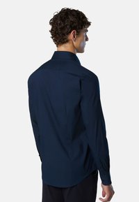 Camicia a maniche lunghe blu navy con colletto a bottoni, texture liscia e orlo dritto, con una silhouette aderente e dettagli a bottoni sui polsini.