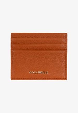Portacarte piccolo in pelle marrone con quattro fessure orizzontali e logo dorato "COCCINELLE" posizionato al centro in basso.