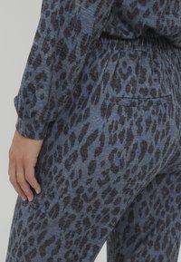 Zila leopardu raksta mājas apģērbu komplekts ar mīkstu, teksturētu apdari. Iezīmē elastīgu jostasvietu un kabatu aizmugurē.
