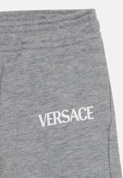 Joggers de algodón gris con una textura suave, que cuentan con una cintura elástica y el logo blanco "VERSACE" impreso en el lado izquierdo.
