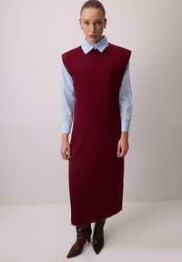 Burgundia sansavärvuline kleit ümmarguse kaelusega, kihilise helesinise kraega särgi peal, koos pruunide teravatipuliste saabastega.