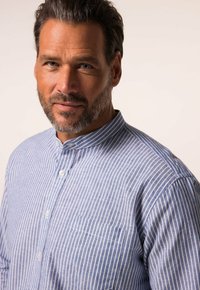 Camicia a righe blu e bianche con colletto alla coreana, dotata di taschino sul petto e tessuto leggero. Il design presenta sottili linee verticali.