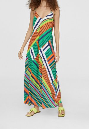 Donna che indossa un vestito lungo senza maniche a righe colorate con scollo a V e sandali aperti lime verdi.