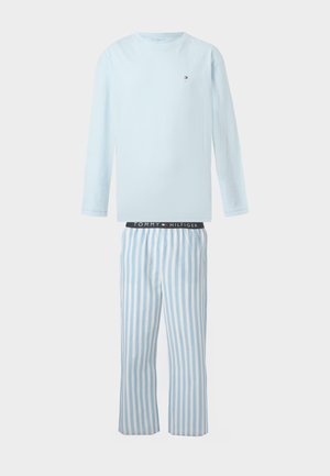 Top de manga larga azul claro con pequeño logo y pantalones a rayas verticales azules y blancos con cinturilla negra con la marca "Tommy Hilfiger."