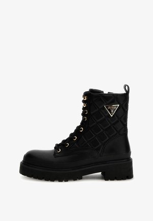 Stivaletto nero con lacci, tomaia sintetica trapuntata, occhielli in tonalità oro, distintivo del logo in evidenza e suola in gomma nera molto spessa.