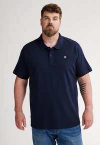 Marineblauwe polo-shirt van een zachte stof, met een drieknoopsluiting, korte mouwen en een klein logo op de borst.