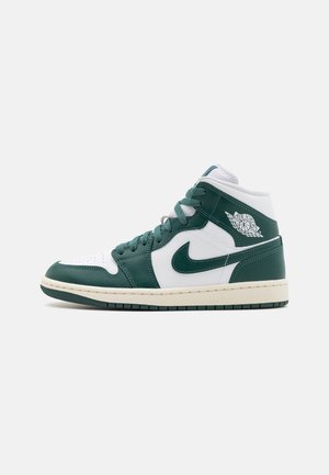 Mid-top sneaker met groen en wit leer, opvallend Nike-logo, geperforeerde neus en gestructureerde zool met een lichte crèmekleurige middenzool.