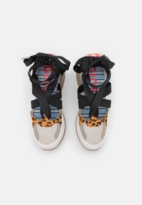 Mnohobarevné tenisky s leopardím vzorem na špičce, béžovým textilním tělem a černými stuhami přes pruhovanou stélku.