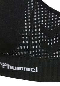 Svart sport-bralette med texturerad tyg, med ett framdesign av vita prickar och en logo på bandet. Justerbara remmar är inte synliga.