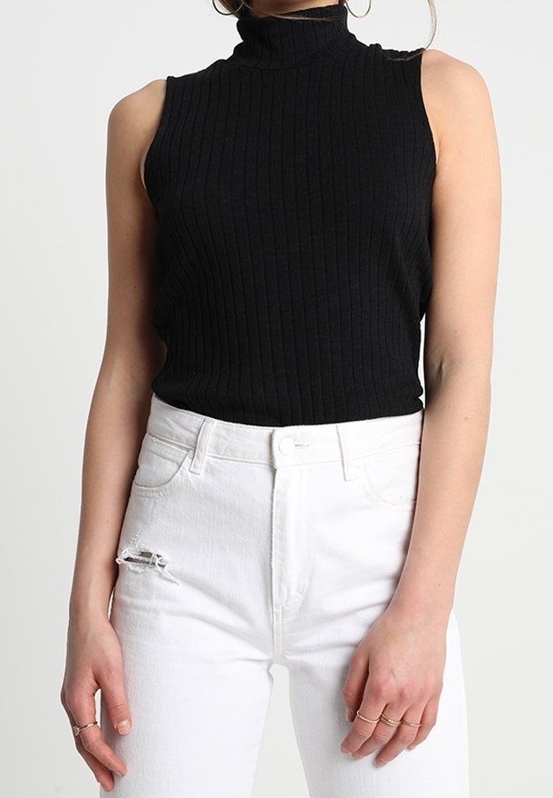 Černý žebrovaný top bez rukávů s vysokým límcem, spárovaný se sepranými bílými džíny, s přiléhavým střihem a jemnou strukturou.