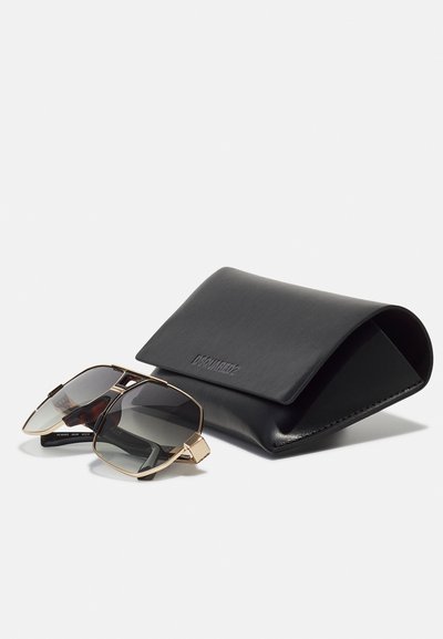 Octagonal sunglasses with gradient gray lenses, gold metal accents, and black acetate arms next to a sleek black leather case.