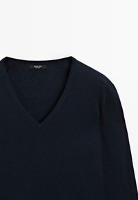 Maglione a V in blu scuro con etichetta Massimo Dutti, che mette in mostra un tessuto morbido e un design minimalista.