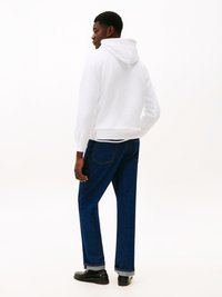 Vit huva sweatshirt med en avslappnad passform, i kombination med mörkblå raka jeans och svarta skor, med uppvikta ärmar.