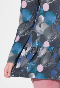 Langärmliges Kleid aus dunkelgrauem Stoff mit einem bunten abstrakten Muster, das blaue, pinke und grüne Kreise sowie weiße Zweigakzente zeigt.
