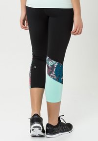 Černé legíny s pastelově mátovými akcenty a živou, vzorovanou vsadkou s tropickými listy. Vyrobené z elastického, hladkého materiálu.