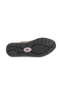 Zwart rubberen zool met een textuur patroon voor grip en een cirkelvormig logo detail. Heeft een brede basis en diepe groeven voor tractie.