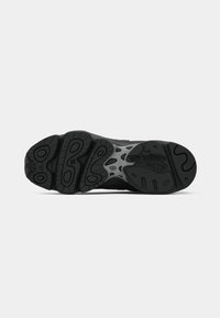 Semelle de chaussure de sport noire avec une surface en caoutchouc texturé comportant de multiples motifs de semelle et rainures pour une meilleure adhérence, rehaussée d'une accentuation grise.
