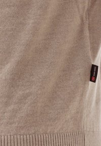 Beige gestrickter Pullover mit geripptem Saum, der ein Logo-Tag an der Seite aufweist. Weicher Stoff, leichtes Material und normale Passform.