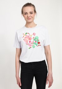 T-shirt bianco in cotone con un'illustrazione colorata di elefanti giocosi e caramelle, dal taglio rilassato e maniche corte.