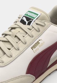 White and burgundy sneaker featuring textured suede and leather, gold logo, beige accents, and flat laces on a light sole.