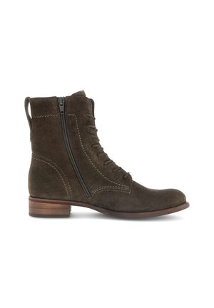 Stivaletto in suede marrone con punta rotonda, chiusura con zip laterale e dettagli di cucitura a contrasto. Tacco in legno piatto.