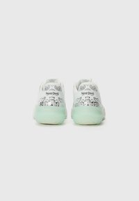 Hvite sneakers med sølvdetaljer, som har en gjennomsiktig mintgrønn såle. Teksten "Snoop Dogg" er trykt på hælen, med dekorative mønstre.
