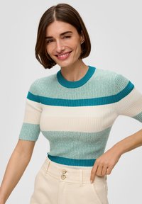 Gestreiften, ribbeligen Kurzarmoberteil in Teal, Creme und Mint mit rundem Halsausschnitt. Kombiniert mit cremefarbenen, hochtaillierten Hosen mit Knopfverschluss.